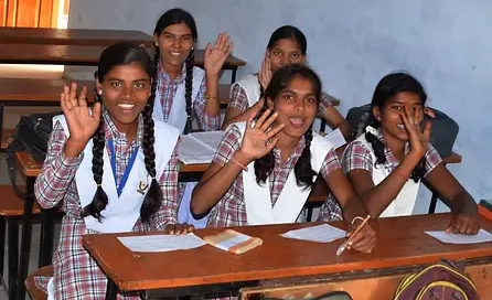 Five 10th grade girls sitting in a classroom and waving to the camera.